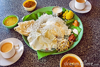 Hot coffee and plate with South Indian food thali with rice and spicy vegetables, on palm leaf in indian cafe. Stock Photo
