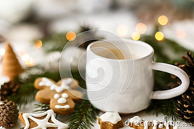 Coffee, homemade gingerbread cookies, pine cones decorations and warm lights on white table Stock Photo