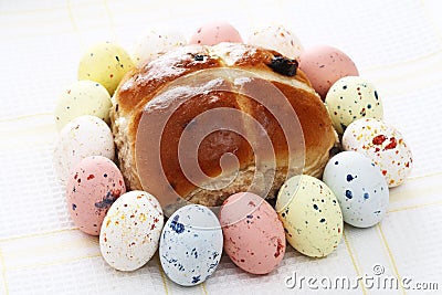 Hot cross bun surrounded by Speckled easter eggs Stock Photo