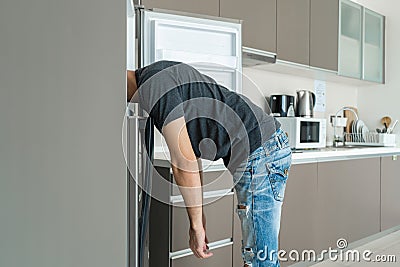 On a hot day, the guy cools with his head in the refrigerator. Broken air conditioner Stock Photo