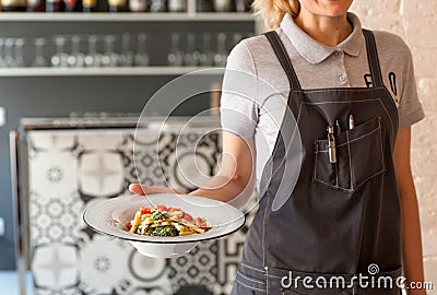 Hot dish in hand of waitress, plate of tasty pasta for hungry visitors of a restaurant Editorial Stock Photo