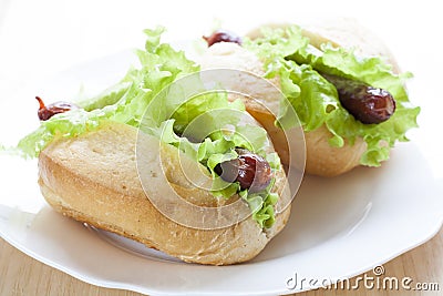 Hot dog. Grilled hot dogs with fresh salad lettuce on wooden table. Stock Photo