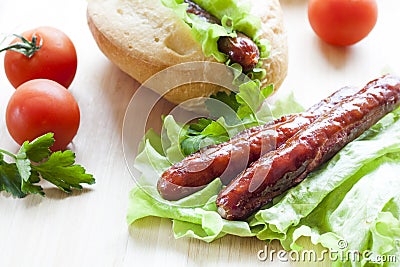 Hot dog. Grilled hot dogs with fresh salad lettuce on wooden table. Stock Photo