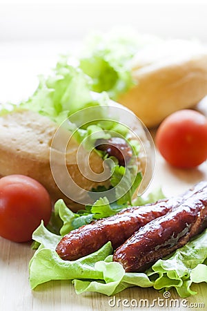 Hot dog. Grilled hot dogs with fresh salad lettuce on wooden table. Stock Photo