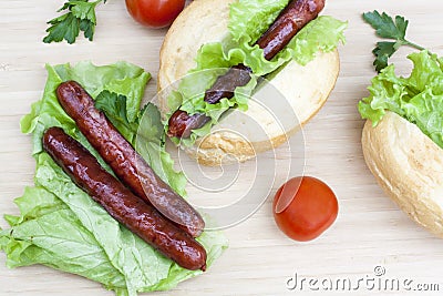 Hot dog. Grilled hot dogs with fresh salad lettuce on wooden table. Stock Photo