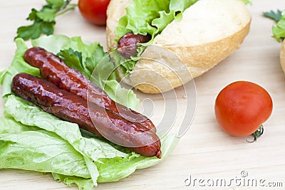 Hot dog. Grilled hot dogs with fresh salad lettuce on wooden table. Stock Photo