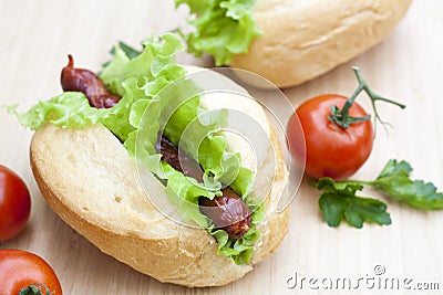 Hot dog. Grilled hot dogs with fresh salad lettuce on wooden table. Stock Photo