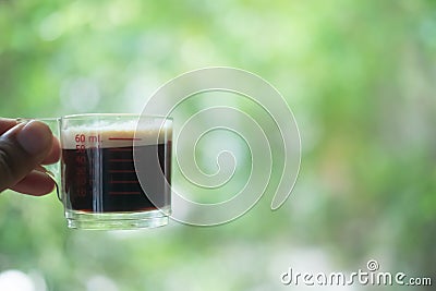Hot espresso shots in handle glass in hand Stock Photo