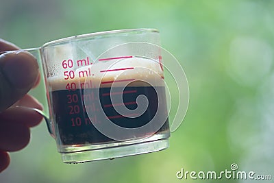 Hot espresso shots in handle glass in hand Stock Photo