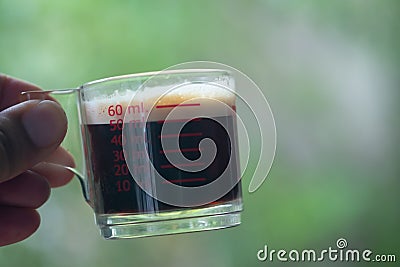 Hot espresso shots in handle glass in hand Stock Photo