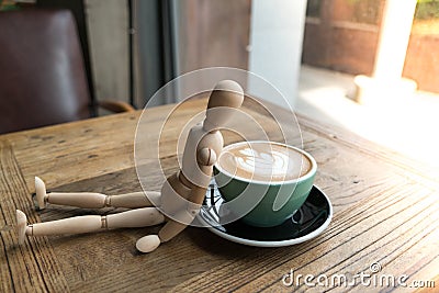 Hot mocha coffee or capuchino in the green cup lean by wood man on the wooden table Stock Photo