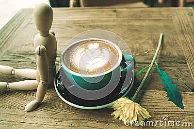 Hot mocha coffee or capuchino in the green cup lean by wood man on the wooden table Stock Photo