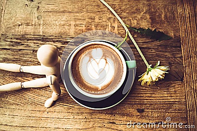 Hot mocha coffee or capuchino in the green cup lean by wood man on the wooden table Stock Photo