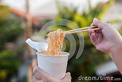 Hot noodle Cup. Noodle cup Ready made. Eating Instant Noodles with a Plastic Fork. Junk food Instant noodles are eating the popula Stock Photo