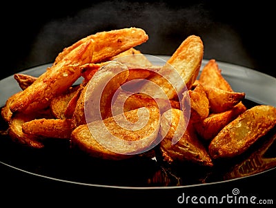 Hot potato wedges on black plate Stock Photo