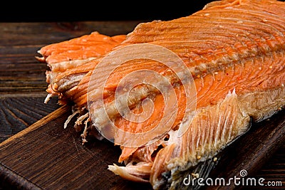 Hot smoked salmon trim and leftovers with bones and fins on dark wooden background Stock Photo