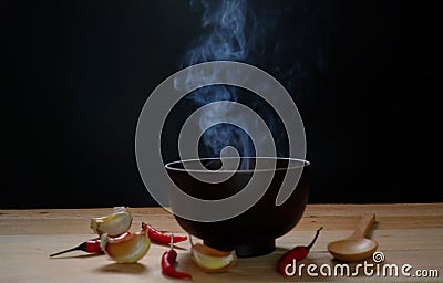 Hot soup in bowl with smoke on wood table and black background Stock Photo