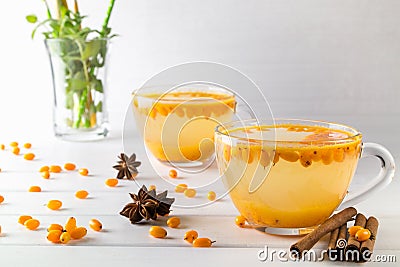 Hot spicy beverage with sea buckthorn in glass cups with fresh raw sea buckthorn berries Stock Photo