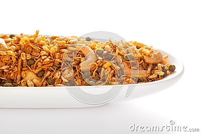Hot spicy Kashmiri Mixture Namkeen snacks in a white ceramic oval bowl made with dry fruits, peanuts, corn flakes. Stock Photo