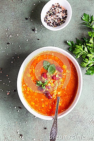 Hot and spicy, thick lentil and red bean soup with canned tomatoes and coriander. Concrete background, selective focus. Top view Stock Photo