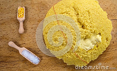 Hot steaming polenta with wooden scoop with cornmeal amd salt, bellows cheese on a old wooden board Stock Photo