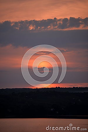 Hot sunset above the forest. Refelctions of red clouds in the water of the lake. bright colors at the end of a summer day Stock Photo