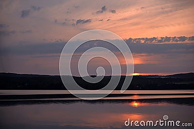 Hot sunset above the forest. Refelctions of red clouds in the water of the lake. bright colors at the end of a summer day Stock Photo