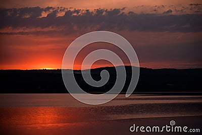 Hot sunset above the forest. Refelctions of red clouds in the water of the lake. bright colors at the end of a summer day Stock Photo