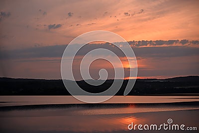 Hot sunset above the forest. Refelctions of red clouds in the water of the lake. bright colors at the end of a summer day Stock Photo