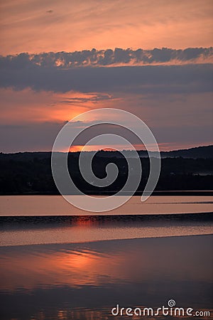 Hot sunset above the forest. Refelctions of red clouds in the water of the lake. bright colors at the end of a summer day Stock Photo