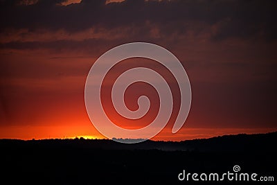 Hot sunset above the forest. Refelctions of red clouds in the water of the lake. bright colors at the end of a summer day Stock Photo