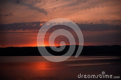 Hot sunset above the forest. Refelctions of red clouds in the water of the lake. bright colors at the end of a summer day Stock Photo