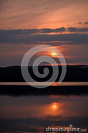 Hot sunset above the forest. Refelctions of red clouds in the water of the lake. bright colors at the end of a summer day Stock Photo