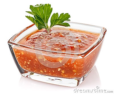 Hot tomato sauce with parsley leaves in a small transparent glass square bowl isolated on white background Stock Photo