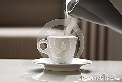 Hot water flowing from a teapot in a white cup Stock Photo