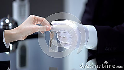 Hotel administrator hand in glove giving lady key on chain, vip service, luxury Stock Photo