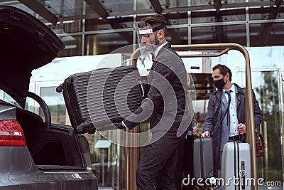 Hotel employee loading customer luggage into a car trunk Stock Photo