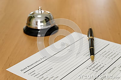 Hotel reservation form and luxury pen at reception concierge desk. With a bell ring for guest to call for a service, attention. Stock Photo