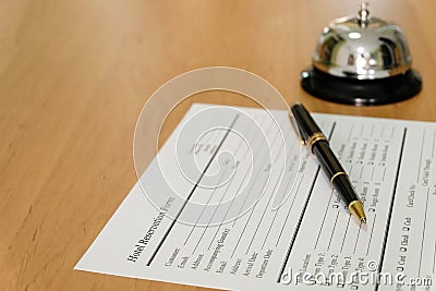 Hotel reservation form and luxury pen at reception concierge desk. With a bell ring for guest to call for a service, attention. Stock Photo