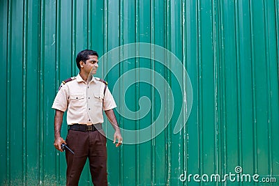 Hotel security guard in Sri Lanka against a green fence Editorial Stock Photo