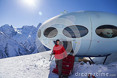 Hotel in the shape of an alien flying saucer standing high in the mountains among the snow capped mountain peaks. Dombay Editorial Stock Photo