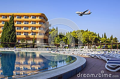 A hotel for tourists, a swimming pool with sun beds and an airplane flying over them in the early summer morning. Croatia, Europe Editorial Stock Photo