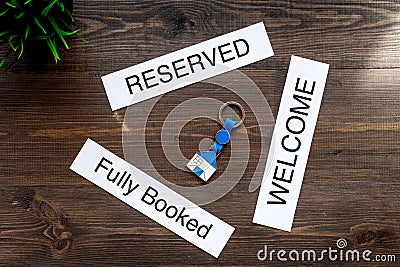 At the hotel. Words welcome, fully booked, reserved on dark wooden table top view Stock Photo