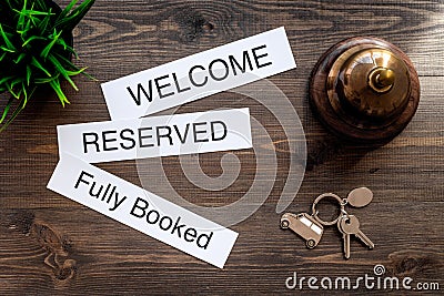 At the hotel. Words welcome, fully booked, reserved on dark wooden table top view Stock Photo