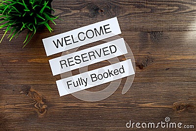At the hotel. Words welcome, fully booked, reserved on dark wooden table top view copyspace Stock Photo