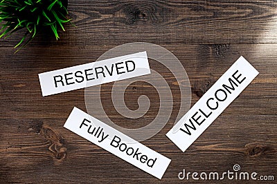 At the hotel. Words welcome, fully booked, reserved on dark wooden table top view copyspace Stock Photo