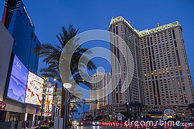 Hotels along a street with colorful digital billboards, lush green palm trees, people walking, cars driving on the street Editorial Stock Photo