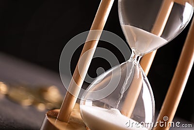Hourglass with flowing sand on table. Time management Stock Photo
