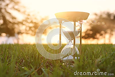 Hourglass in the grass time during sunset. vintage style. Stock Photo