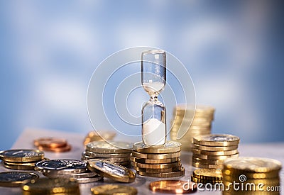 Hourglass and many coins Stock Photo